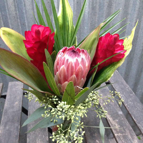 Tropical bouquet with pink protea and red ginger flowers