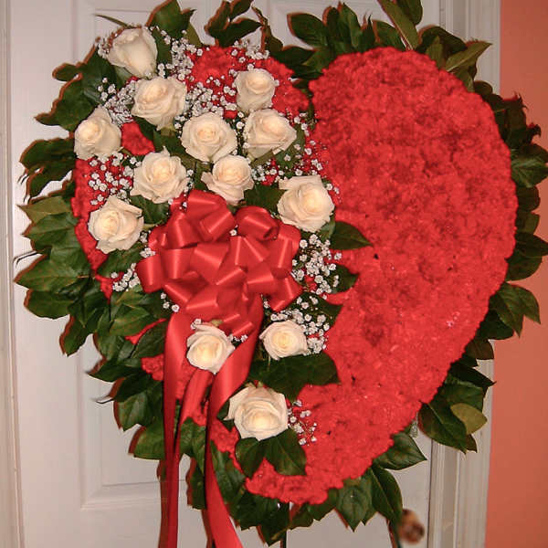 Heart-shaped floral spray with white roses and a red bow