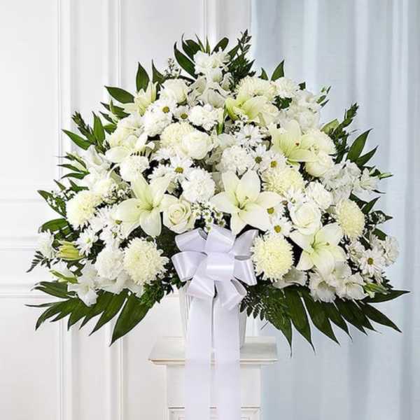 White floral spray with lilies and chrysanthemums in a vase, tied with a white ribbon