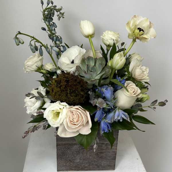 White and pale pink flowers in a wooden box with blue accents and a succulent