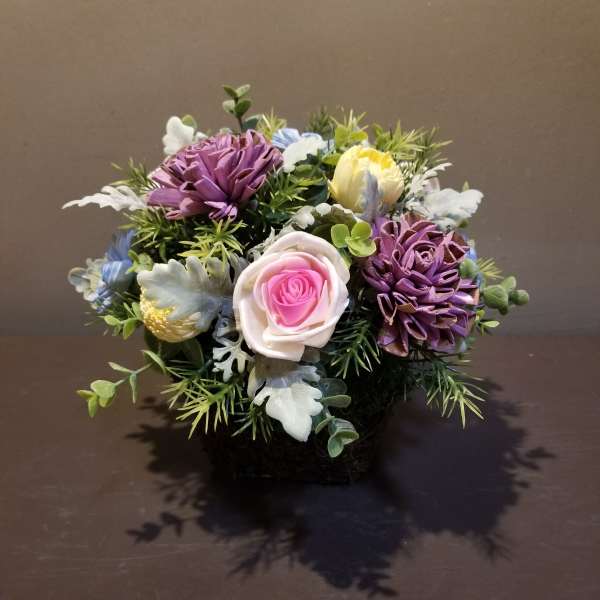Small bouquet of purple, pink, yellow, and white flowers in a low container