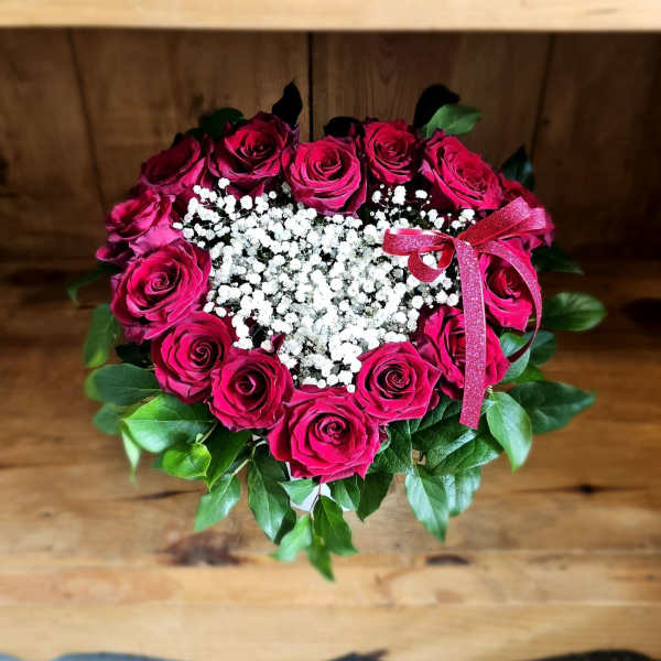 Heart-shaped bouquet of pink roses with white baby's breath and a pink ribbon