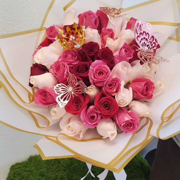 Bouquet of pink and white roses wrapped in white paper with gold trim