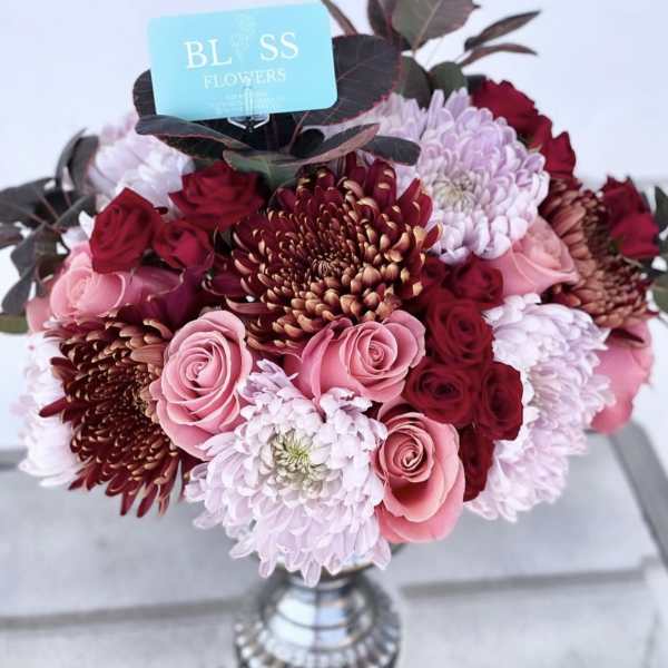 Bouquet of pink and burgundy flowers in a silver vase