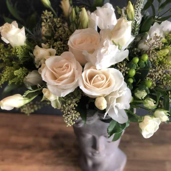 Bouquet of pale peach roses and white blooms in a gray vase