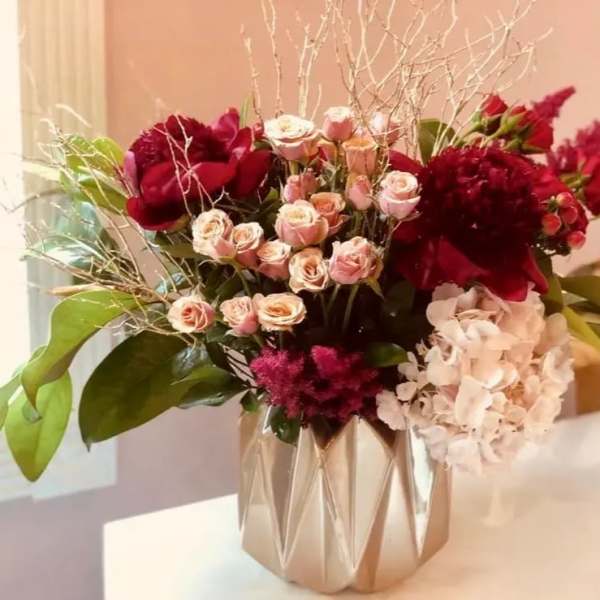 Bouquet of red and blush flowers in a metallic vase