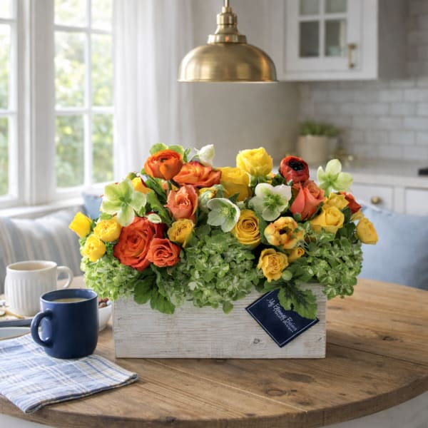 Mixed bouquet of orange, yellow, and white flowers in a white wooden box
