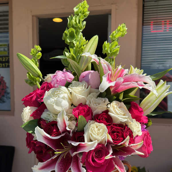 Bouquet of pink and white roses with lilies in a painted ceramic vase