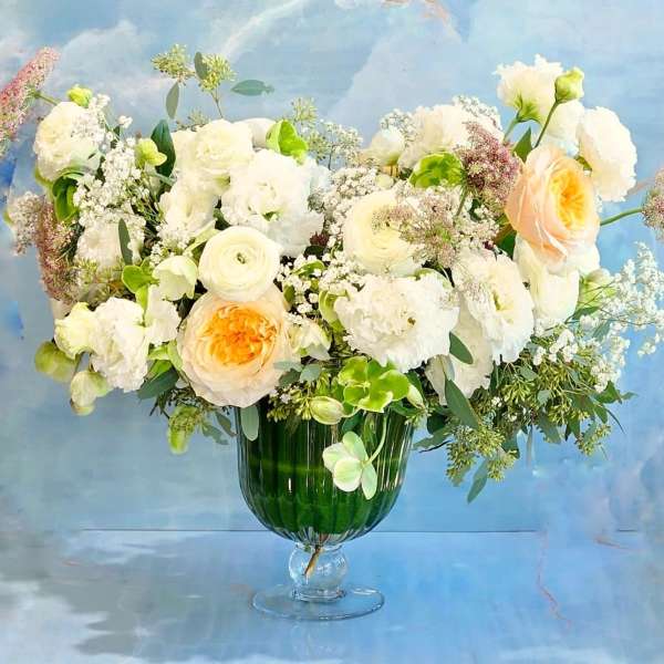 White and peach flowers arranged in a green glass vase
