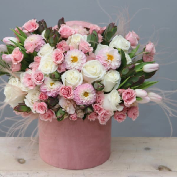Round pink hatbox arrangement of soft pink and white roses, dahlias, carnations, and tulips
