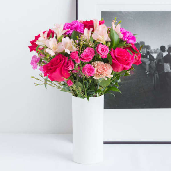 Bouquet of pink and white flowers in a tall white vase