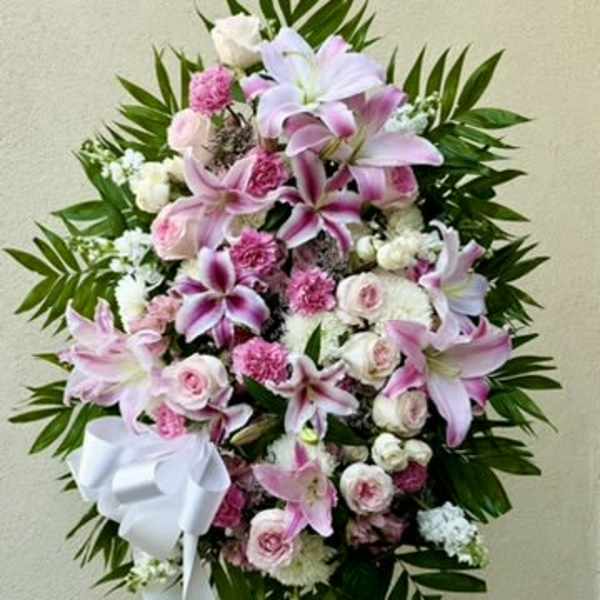 Pink and white floral standing spray with a white ribbon