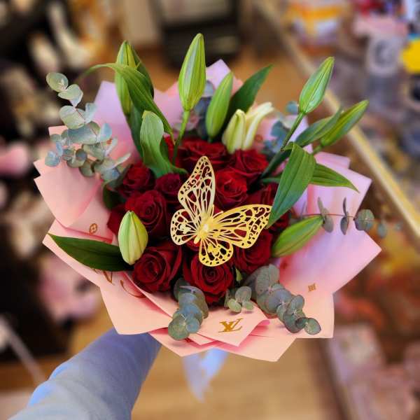 Bouquet of red roses with lily buds in pink wrapping