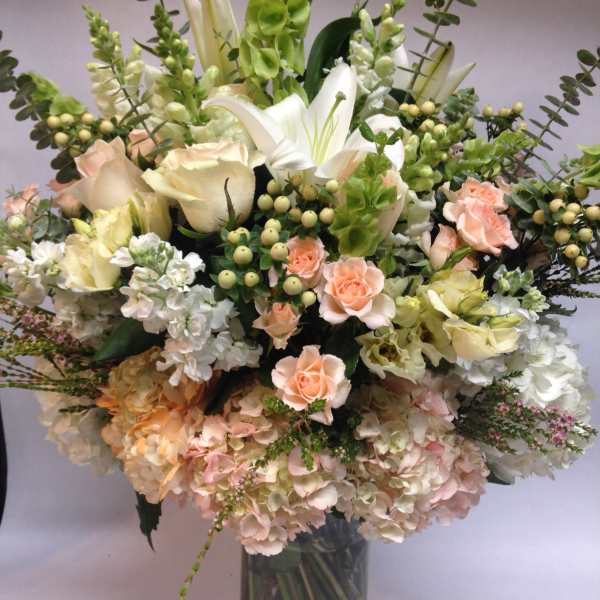 Tall bouquet of white and peach flowers in a glass vase