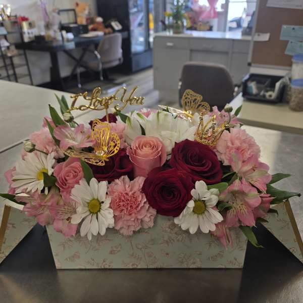 Pink and white flower arrangement in a floral box with gold toppers