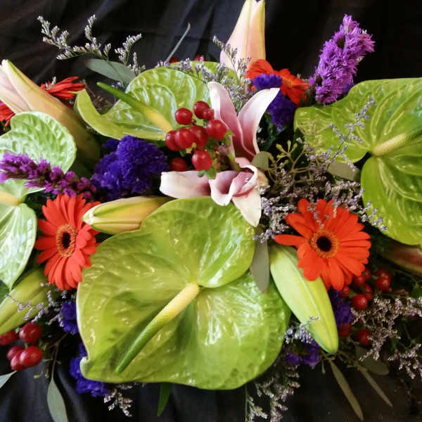 Mixed bouquet with orange gerbera daisies, lilies, and purple flowers