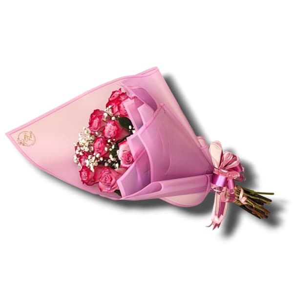 Bouquet of bright pink roses with white filler wrapped in layered pink paper and ribbon