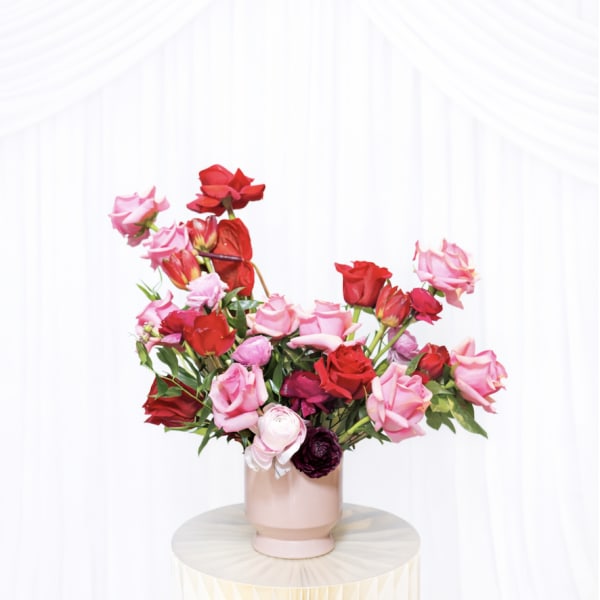Pink and red rose arrangement in a blush vase