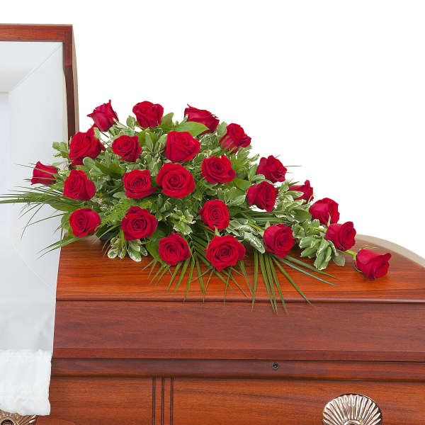 Red rose casket spray arranged on a closed wood casket with white interior