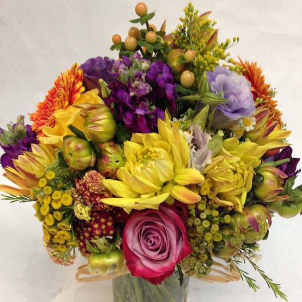 Colorful mixed bouquet in a clear glass vase with roses and daisies