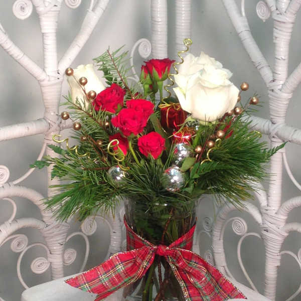 Red and white roses in a glass vase with a plaid ribbon