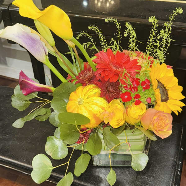 Colorful mixed flower arrangement with calla lilies, gerbera daisies, and roses in a glass vase