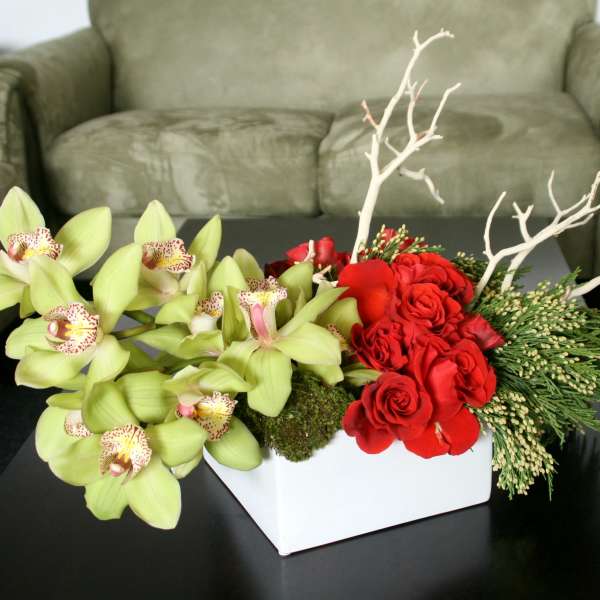 Red roses and green orchids in a white rectangular vase