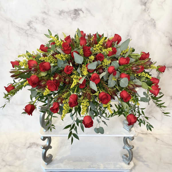 Large arrangement of red roses with yellow filler flowers on a white stand