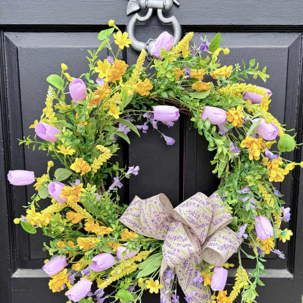 Floral wreath with purple and yellow blooms on a black door