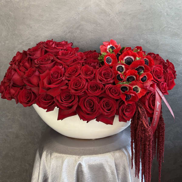 Large red rose arrangement in a white bowl with red anemones