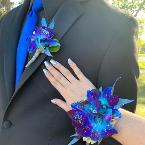 Blue and purple orchid boutonniere and matching wrist corsage on a black suit