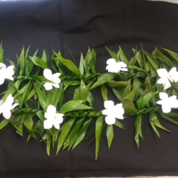 White flowers arranged in a long green garland on a black background