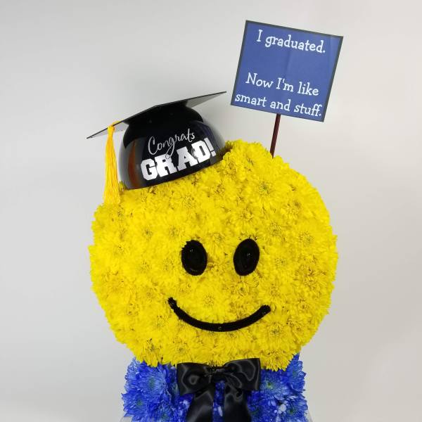 Smiley-face floral arrangement with graduation cap and sign