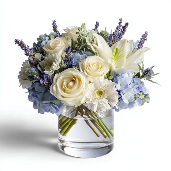 White roses and lilies with blue hydrangeas in a glass vase