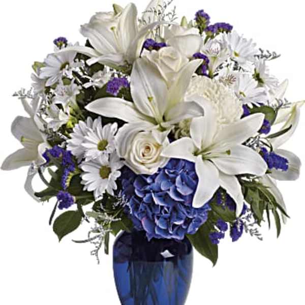 White lilies and daisies with blue hydrangea in a blue vase