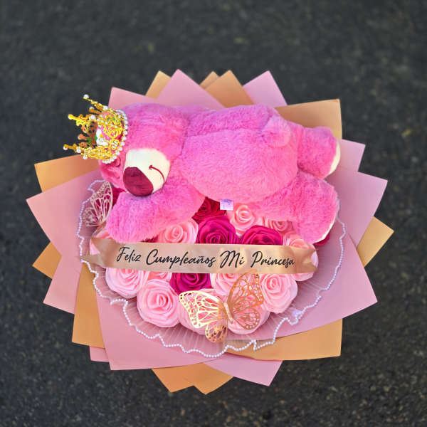 Pink teddy bear on a bouquet of pink roses with a birthday ribbon