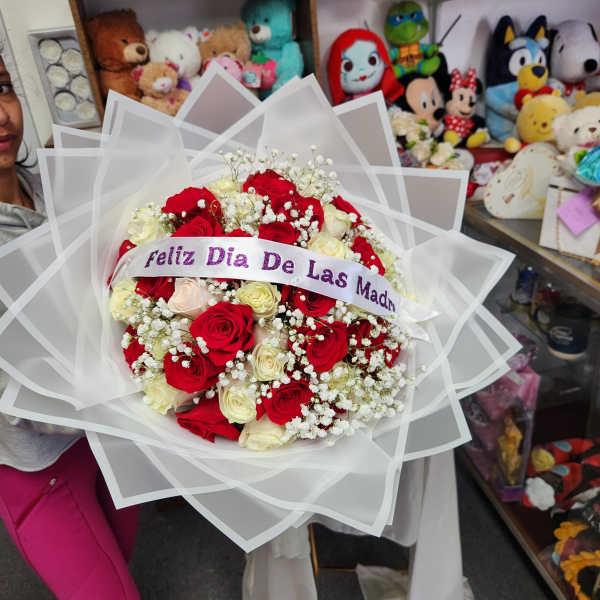 Bouquet of red and cream roses wrapped in white paper with a ribbon