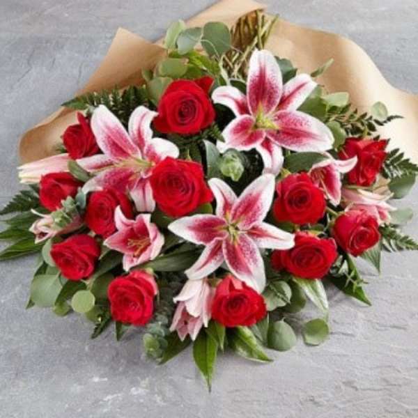 Bouquet of red roses and pink lilies wrapped in brown paper