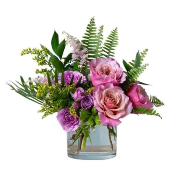 Pink and purple roses arranged in a clear glass vase