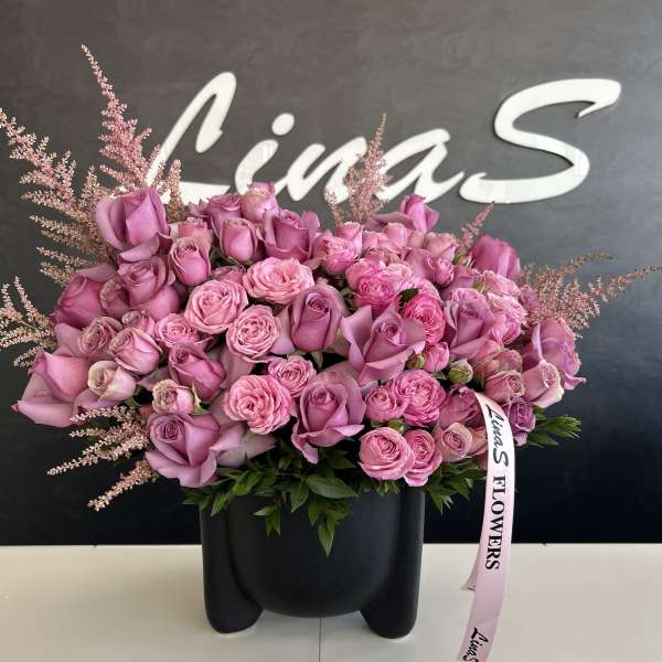 Pink rose bouquet in a black vase with a ribbon