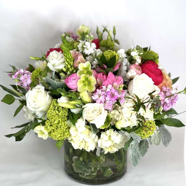 Mixed bouquet of white, pink, and green flowers in a glass vase