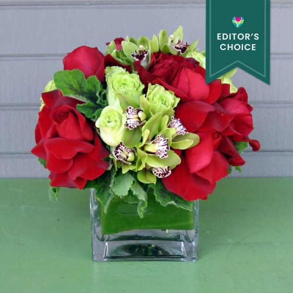 Red roses and green orchids in a clear square vase