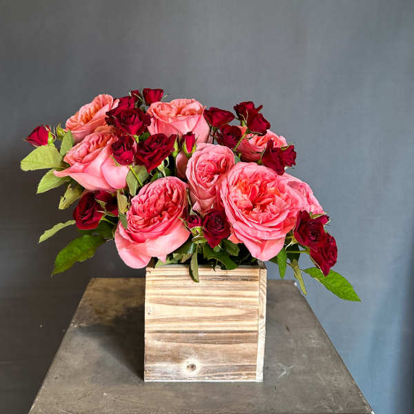 Pink and red roses arranged in a wooden box