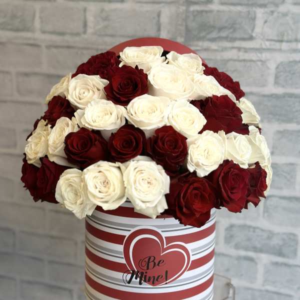 Red and white roses in a striped heart box with "Be Mine" text