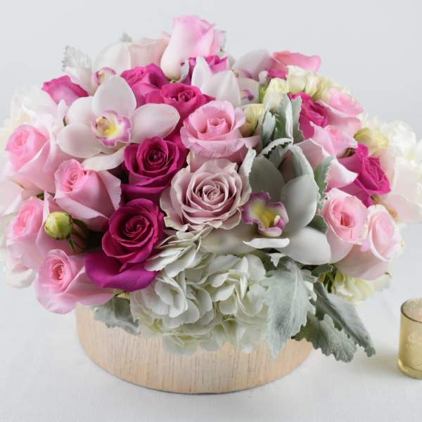 Pink and white rose arrangement in a round wooden container