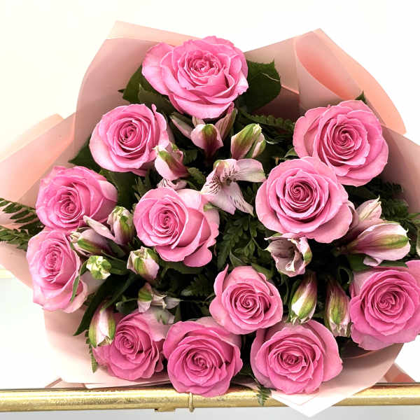 Bouquet of pink roses and light pink alstroemeria wrapped in soft pink paper