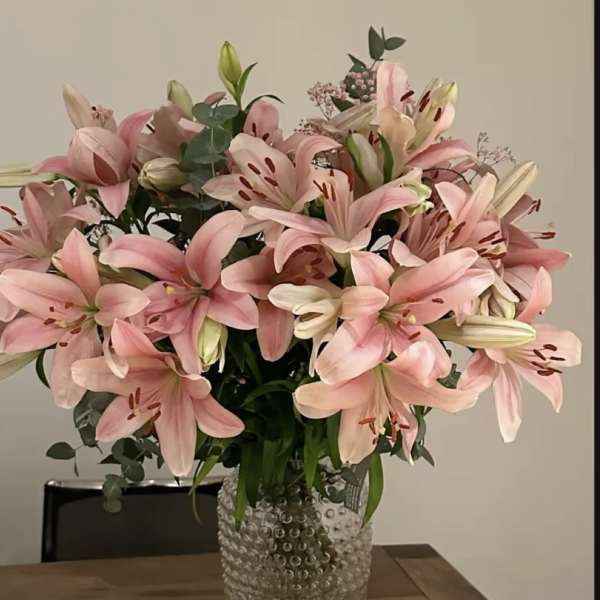 Pink lilies arranged in a clear textured vase