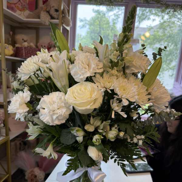 White floral bouquet in a glass vase with a white ribbon