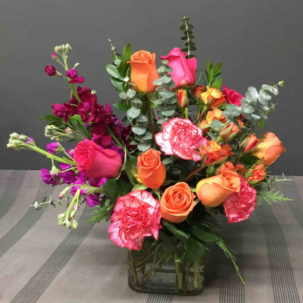 Mixed bouquet of orange and pink roses with carnations in a glass vase