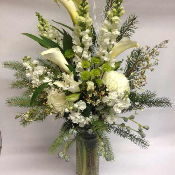 Tall white floral arrangement in a glass vase with calla lilies and snapdragons